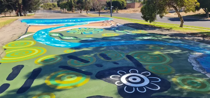 Aboriginal river story mural flowing along an asphalt road