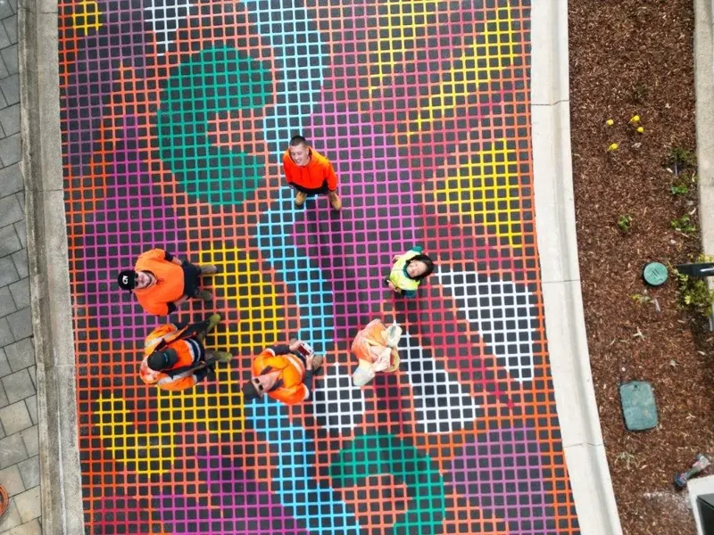 Aerial view of applicators installing a colourful street mural