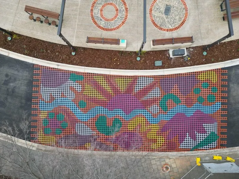 Aerial view of a mosaic style street mural at a landscaped roundabout