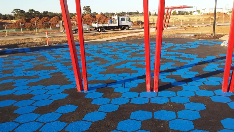 Blue hexagon pattern plaza surfacing under red sculpture poles