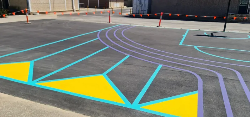 Fresh court line markings in teal and yellow on asphalt