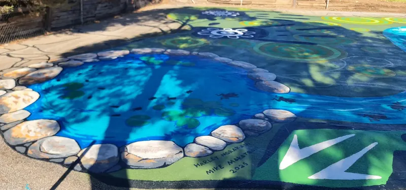 Waterhole themed playground mural with painted stones and turtles