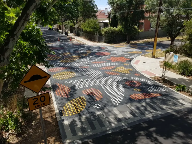 Decorative traffic calming treatment at a suburban intersection with speed hump signage